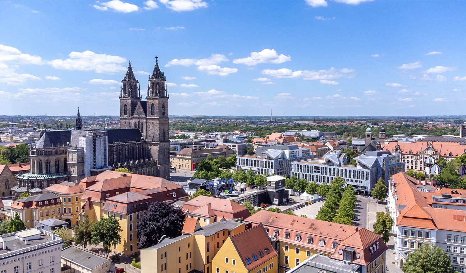 Luftaufnahme des Magdeburger Doms und der Innenstadt bei Sonnenschein – gepflegte Dächer und saubere Dachrinnen, dafür sorgt die Firma Bloehm Dachrinnenreinigung in Magdeburg.